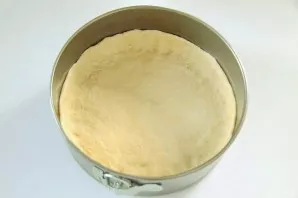 Divide the dough into two parts. Roll out one part on the table and carefully transfer to a greased baking sheet. Form higher edges with ...