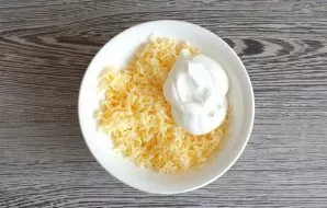 Grate the cheese on a fine grater, add sour cream. Stir.