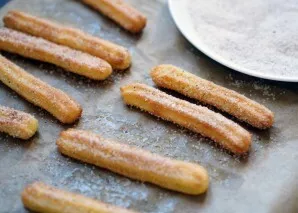 Place in an oven preheated to 200 degrees for 15 minutes. While our churros are baking, take a wide plate, pour sugar into it and add cin...