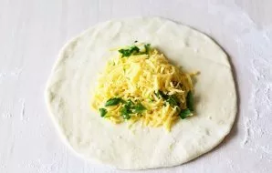 Sprinkle the work surface with a little flour and roll part of the dough with a rolling pin into a thin round cake. Put 2 tablespoons of ...