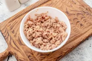 Open a can of tuna, drain the juice, crush the canned food with a fork.