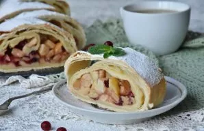 From puff pastry prepared strudel with apples and lingonberries. Allow to cool before cutting. When serving, sprinkle the roll with icing...