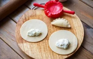 Put a teaspoon of cottage cheese filling on each circle of dough. Pinch the edges of the dough carefully.