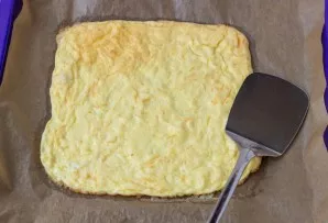 The omelette is ready. Remove from all sides with a spatula so that it hangs from the paper.