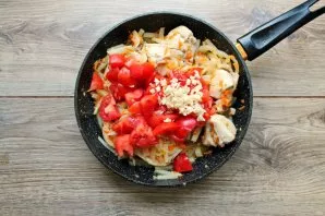 Cut the tomatoes into slices and put in a pan. Peel the garlic, chop it and add it to the pan.