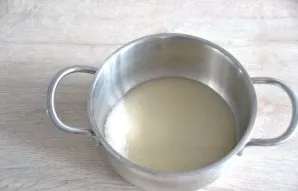 To prepare the protein cream, pour 180 grams of sugar into a saucepan, pour hot water over it, and put it on a low heat.