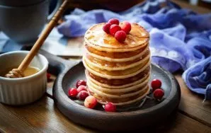 Put pancakes in a pile on a plate, pour with your favorite syrup, garnish with berries and serve.
