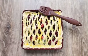 Make a grid from the smaller part of the dough and place it on top of the filling. Pinch the edges and brush the top with the beaten egg ...