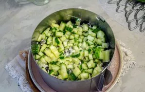 Wash, dry and cut fresh cucumbers into small cubes. Lay out the next layer. Lightly brush with mayonnaise.