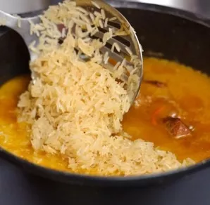 After 1 hour, remove the garlic and add the rice to the pot. Add more water if necessary.