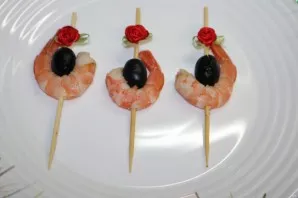 Clean the shrimp. pierce with a skewer and garnish with olives.