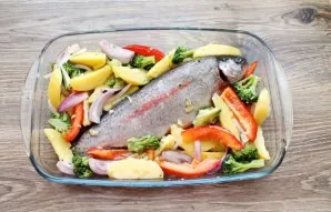 Lubricate the baking dish with vegetable oil and add the fish. Spread the prepared vegetables around the fish.