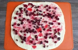 Roll out the dough into a 0.3 cm thick layer. Wipe the juice from the filling and put it on the layer. Sprinkle dried cranberries on top.